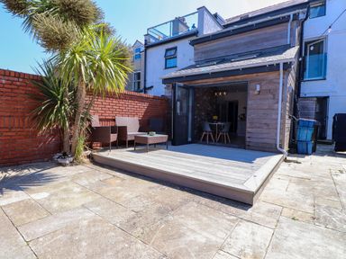 A garden with decking and seating area at Ty Haul Rhosneigr