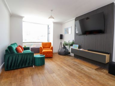 A living room with a green sofa and orange armchair at Ty Haul in Rhosneigr