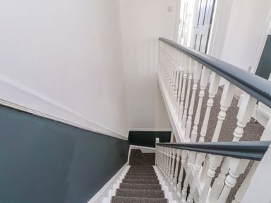 A staircase with a handrail and carpet at Ty Haul in Rhosneigr