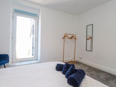 A bedroom with a door, hangers, towels, and a mirror at Ty Haul in Rhosneigr