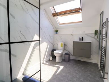 A bathroom with a shower, toilet, sink and skylight at Ty Haul in Rhosneigr