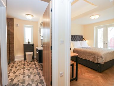A bathroom with a toilet and sink next to a bedroom with a bed and a window at How Hill Farm Cottage in Greystoke