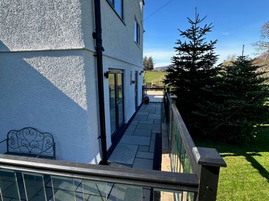 An outdoor area with a patio and glass doors at How Hill Farm Cottage in Greystoke