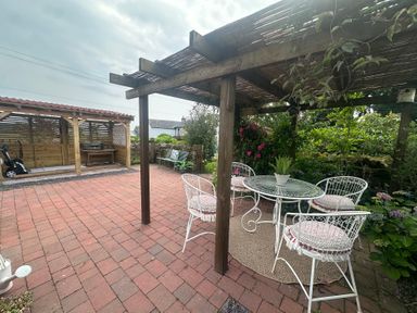 A garden with a table and chairs under a pergola at How Hill Farm Cottage in Greystoke