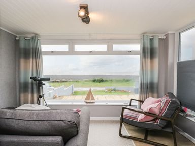 A sitting room with a telescope and model sailboat by the window at The Chalet in Coulderton near Egremont Cumbria