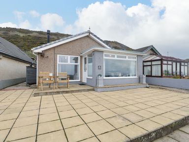 A single-story house with a tiled patio and two wooden chairs at The Chalet in Coulderton near Egremont Cumbria