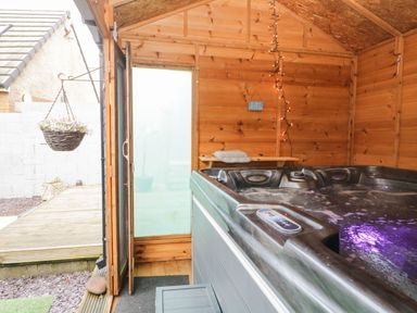 An indoor wooden room with a hot tub and hanging light string at The Chalet in Coulderton near Egremont Cumbria