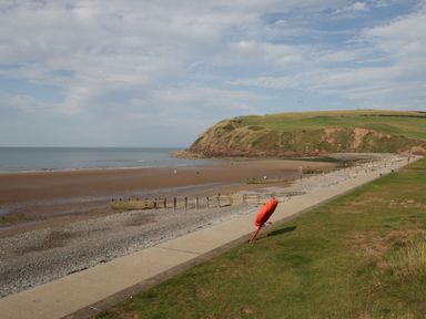A coastal path next to a beach and grassy hill with a red lifebuoy at The Chalet in Coulderton near Egremont Cumbria