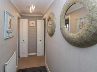 A hallway with a carpet a radiator two round mirrors and white doors at The Chalet in Coulderton near Egremont Cumbria