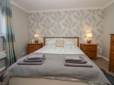 A bedroom with a double bed with folded towels bedside tables with lamps and a chest of drawers at The Chalet in Coulderton near Egremont Cumbria