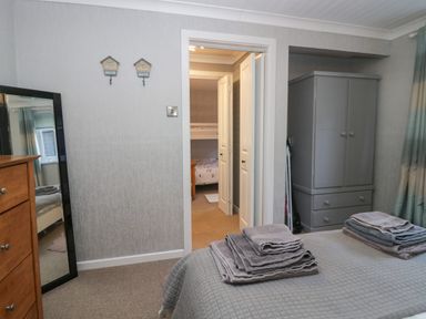 A bedroom with a bed folded towels a gray wardrobe a wooden chest of drawers and a mirror at The Chalet in Coulderton near Egremont Cumbria