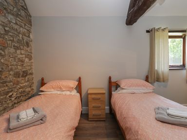 A bedroom with two single beds and a wooden nightstand between at Swallow Barns in Chipping Sodbury
