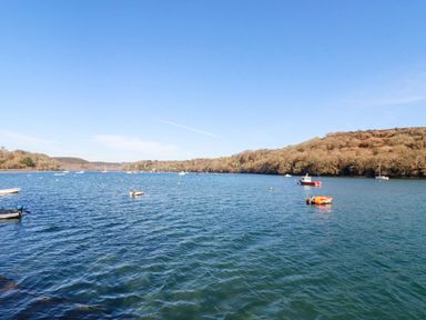 A body of water with small boats and trees on hills at Oakenhurst in Golant