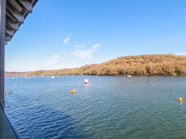 A view of a river or estuary with boats and a wooded hill in the background at Oakenhurst in Golant