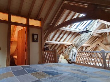 A bedroom with a bed and a wooden railing under a sloped ceiling with skylights at Oakenhurst in Golant