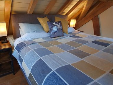 A bedroom with a bed covered by a patchwork quilt with pillows and two bedside tables with lamps at Oakenhurst in Golant