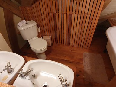A bathroom with a toilet sink and a bathtub with wooden panel walls and floor at Oakenhurst in Golant