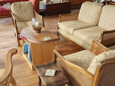 A living area with wooden furniture including chairs a couch and tables with books and a candleholder at Oakenhurst in Golant