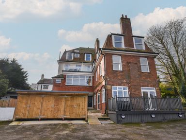 A large brick and white multi-story house with multiple windows and a wooden shed at The Bungalow in Lyme Regis