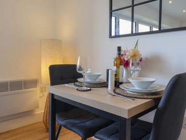 A dining table set for two with chairs a bottle of wine and flowers at The Bungalow in Lyme Regis