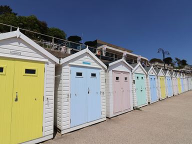 A row of colorful beach huts along a promenade under a clear blue sky