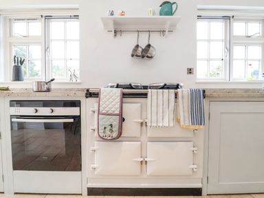 A kitchen with a white stove and oven between two windows with countertop and kitchen utensils at Halsey in Walberswick