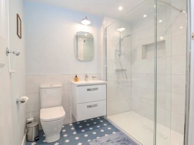 A bathroom with a toilet sink cabinet mirror and glass shower enclosure at Halsey in Walberswick