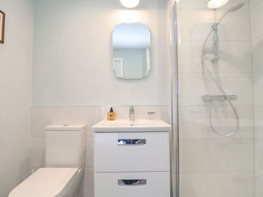 A bathroom with a toilet sink unit mirror and a glass shower enclosure at Halsey in Walberswick