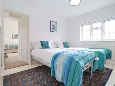 A bedroom with two single beds blue blankets and a patterned rug at Halsey in Walberswick