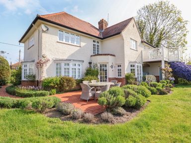 A two story house with a red tiled roof white windows and a garden with outdoor furniture at Halsey in Walberswick