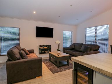 A living room with two sofas a coffee table and a wall-mounted television at 25 Thirlmere in Troutbeck Bridge
