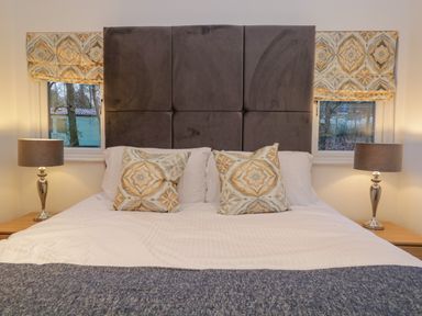 A bedroom with a double bed two patterned pillows two bedside tables and lamps at 25 Thirlmere in Troutbeck Bridge