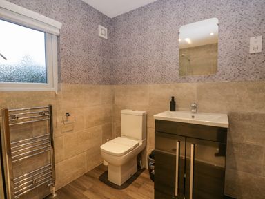 A bathroom with a toilet sink cabinet mirror towel rack and window at 25 Thirlmere in Troutbeck Bridge
