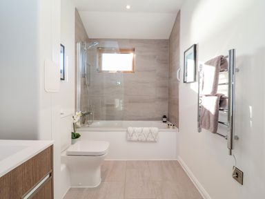 A bathroom with a bathtub shower combination toilet towel rack and window at The Penthouse in Woodbridge