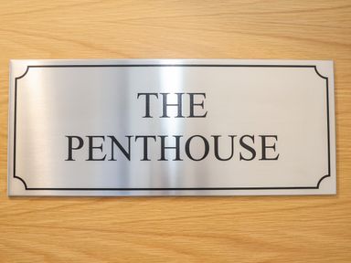 A metal sign with the words The Penthouse on a wooden surface at The Penthouse in Woodbridge