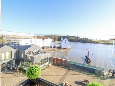 A waterfront view with buildings a dock a boat and a potted plant on a balcony at The Penthouse in Woodbridge
