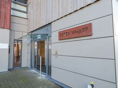 The entrance to a building with glass doors and a sign that says Deben Wharf