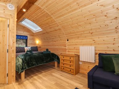 A wooden bedroom with a bed a chest of drawers and a sofa at The Shearer - Crossgate Luxury Glamping in Hartsop near Glenridding