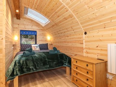 A bedroom with a bed covered with blankets and towels and a wooden dresser at The Shearer - Crossgate Luxury Glamping in Hartsop near Glenridding