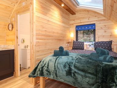 A bedroom with a bed and folded towels in a wood-paneled room with a skylight and a window at The Shearer - Crossgate Luxury Glamping Hartsop near Glenridding