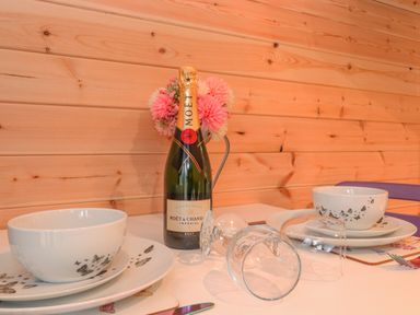 A table set with bowls and plates next to a bottle of champagne and two overturned glasses at Lovies Place - Crossgate Luxury Glamping in Hartsop near Glenridding