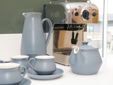 A coffee machine with a blue teapot jug and cups on a kitchen counter at Bryn Mor in Benllech