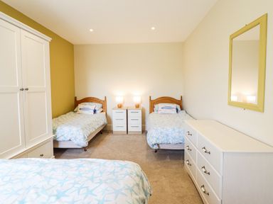 A bedroom with two beds and a wardrobe at Bryn Mor in Benllech