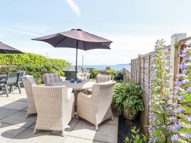 A garden with dining table and chairs under an umbrella at Bryn Mor in Benllech