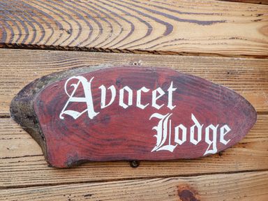 A wooden sign with Avocet Lodge written on it mounted on a wooden wall at Avocet Lodge Tattershall Lakes Country Park