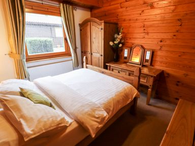 A bedroom with a bed wardrobe and dressing table with mirrors at Avocet Lodge in Tattershall Lakes Country Park