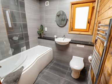 A bathroom with a bathtub shower toilet sink mirror window and towel rack at Avocet Lodge in Tattershall Lakes Country Park