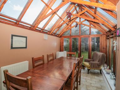 A dining area with wooden table and chairs under glass roof at 2 The Reformed Church in Embleton