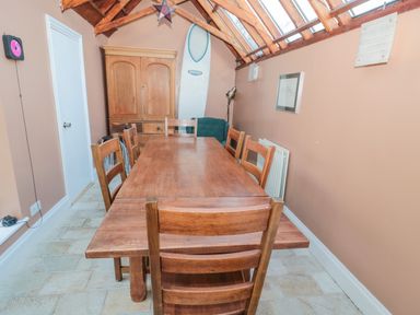 A dining room with a wooden table and chairs wooden cabinet surfboard and skylights at 2 The Reformed Church Embleton