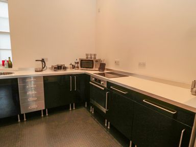 A kitchen with black cabinets white countertops electric stove microwave kettle and knife block at 2 The Reformed Church Embleton